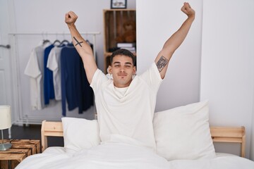 Sticker - Young hispanic man waking up stretching arms at bedroom