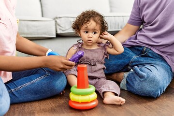 Canvas Print - Couple and daughter smiling confident playing with toys sitting on the floor at home