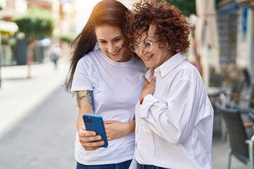 Sticker - Two women mother and daughter standing together using smartphone at street