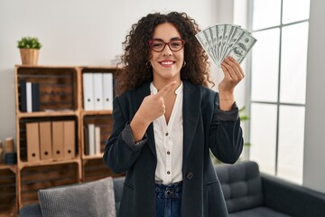 Sticker - Young hispanic woman holding dollars smiling happy pointing with hand and finger