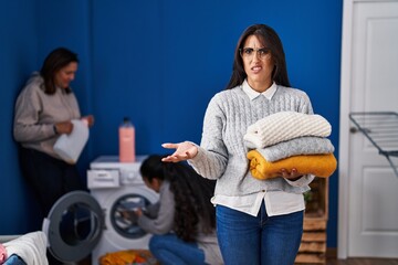 Poster - Three women doing laundry at home clueless and confused expression. doubt concept.