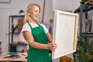 Canvas Print - Young caucasian woman looking at canvas smiling and laughing hard out loud because funny crazy joke.