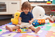 © Krakenimages.com - Adorable hispanic toddler playing xylophone sitting on floor at kindergarten