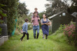 © Caia Image - Happy family walking in grass in backyard garden