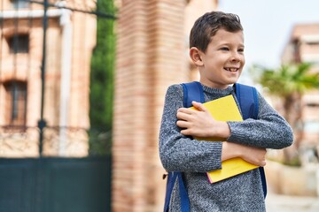 Wall Mural - Blond child student hugging book standing at street