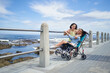© Caia Image - Portrait happy mother and disabled daughter in pushchair at beach