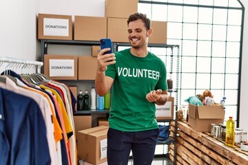 Sticker - Young hispanic man wearing volunteer uniform having video call at charity center