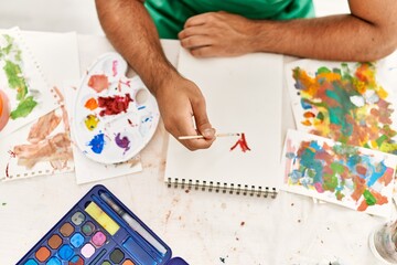 Wall Mural - Young hispanic man drawing on notebook at art studio