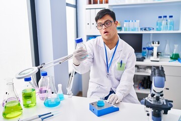 Poster - Down syndrome man wearing scientist uniform measuring liquid at laboratory