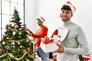 Wall Mural - Two hispanic men couple smiling confident decorating christmas tree at home