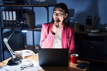 Canvas Print - Chinese young woman working at the office at night looking confident at the camera smiling with crossed arms and hand raised on chin. thinking positive.