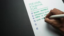 Man's Hand Writing Personal Financial Plan List. Personal Finance Planning Written By Hand. Budgeting, Funding, Saving, Investing. Making List Of Personal Money Goals Avoid Crisis And Recession.