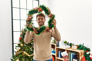 Sticker - Young hispanic man smiling confident holding christmas decor at home