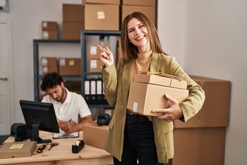 Wall Mural - Young two people working at small business ecommerce smiling happy pointing with hand and finger to the side