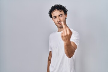 Wall Mural - Hispanic man standing over isolated background showing middle finger, impolite and rude fuck off expression