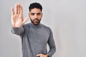 Canvas Print - Hispanic man with beard standing over white background doing stop sing with palm of the hand. warning expression with negative and serious gesture on the face.