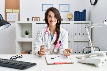 Canvas Print - Young doctor woman holding glass of water and prescription pills smiling with a happy and cool smile on face. showing teeth.