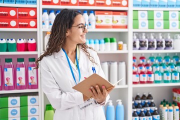 Poster - Young beautiful hispanic woman pharmacist writing on document at pharmacy