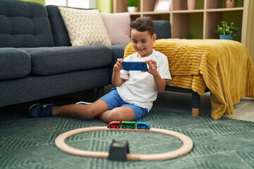 Canvas Print - Adorable hispanic toddler make photo to car game by smartphone sitting on floor at home