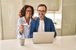 © Krakenimages.com - Middle age hispanic couple smiling confident using laptop and credit card at kitchen