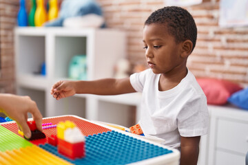 Canvas Print - African american boy playing with construction blocks sitting on table at kindergarten