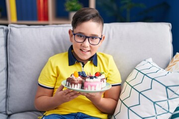 Canvas Print - Young hispanic kid holding cake sweets smiling and laughing hard out loud because funny crazy joke.