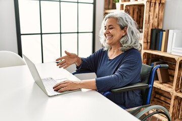 Poster - Middle age grey-haired disabled woman having video call sitting on wheelchair at home.