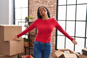 Wall Mural - African american woman smiling confident standing with arms open at new home