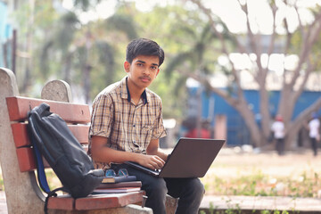 Wall Mural - Portrait of Indian boy using laptop while attending the online classes in park	
