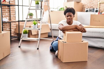 Wall Mural - African american woman sitting on the floor at new home clueless and confused expression. doubt concept.