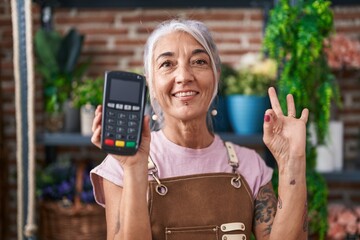 Sticker - Middle age woman with tattoos working at florist shop holding dataphone doing ok sign with fingers, smiling friendly gesturing excellent symbol