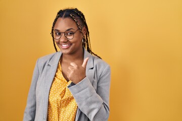 Poster - African american woman with braids standing over yellow background doing happy thumbs up gesture with hand. approving expression looking at the camera showing success.