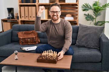 Poster - Middle age caucasian man playing chess sitting on the sofa annoyed and frustrated shouting with anger, yelling crazy with anger and hand raised