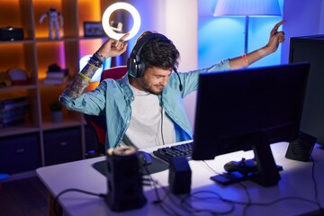 Sticker - Young hispanic man streamer playing video game with winner expression at gaming room