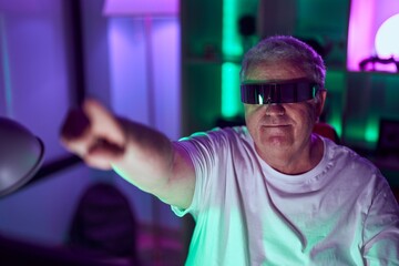 Poster - Middle age grey-haired man streamer playing video game using virtual reality glasses at gaming room