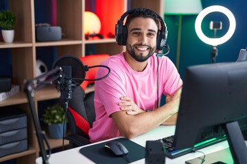 Poster - Young arab man streamer smiling confident sitting with arms crossed gesture at gaming room