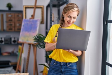 Sticker - Young blonde woman artist smiling confident using laptop at art studio