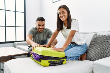 Wall Mural - Latin man and woman couple smiling confident close travel suitcase at home