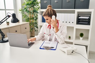 Poster - Young blonde woman wearing doctor uniform talking on the telephone at clinic