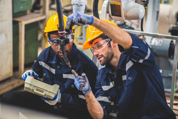 Engineers team mechanic using computer controller Robotic arm for welding steel in steel factory workshop. Industry robot programming software for automated manufacturing technology