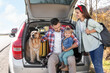 © New Africa - Parents, their daughter and dog sitting in car trunk outdoors. Family traveling with pet