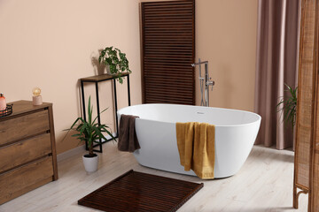 Wall Mural - Stylish bathroom interior with ceramic tub, terry towels and houseplants