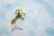 Fresh beautiful bouquet of the first spring forest snowdrops flowers with red and white cord martisor - traditional symbol of the first spring day on sky blue background