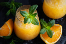 Cold summer orange lemonade with mint and ice in a glass