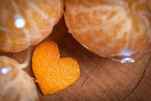Orange Heart Shape Made From Orange Peel On A Cutting Board Surrounded By Soft Focus Citrus Fruits With Fairy Lights.
