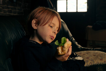 9 year old boy eating a big baguette sandwich