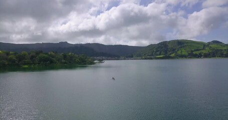 Wall Mural - Magical aerial view of the Lake of Sete Cidades, green landscape view and a small recreational boat crossing the lagoon. São Miguel island in the Azores.