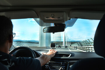 A man in a car on a modern bridge