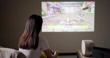 Taiwan 26 November 2022: Woman Play Nintendo Splatoon 3 With Projector On The Wall