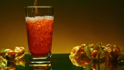 Poster - Beautiful drink is poured into transparent glass. Stock clip. Bright drink is poured into glass on background of ingredients. Fruit around glass with drink on isolated background